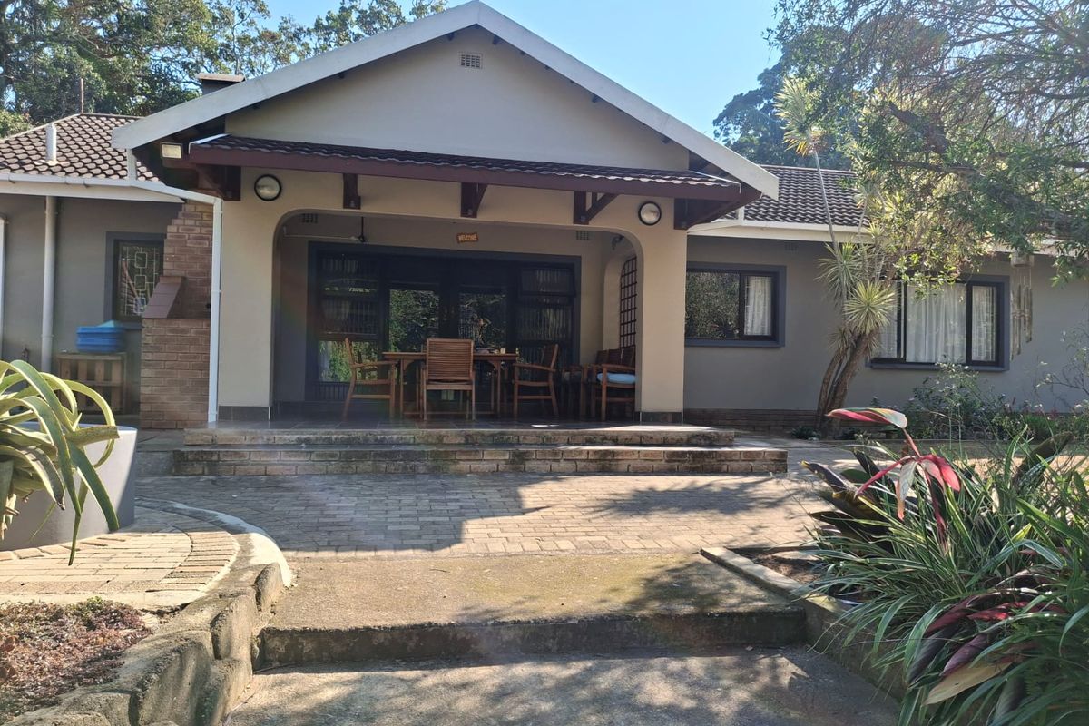 A well-maintained rear exterior featuring a covered patio, brick paving, and a built-in braai area, perfect for outdoor entertaining.