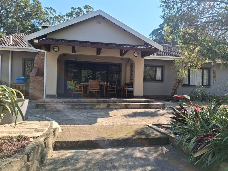 A well-maintained rear exterior featuring a covered patio, brick paving, and a built-in braai area, perfect for outdoor entertaining.