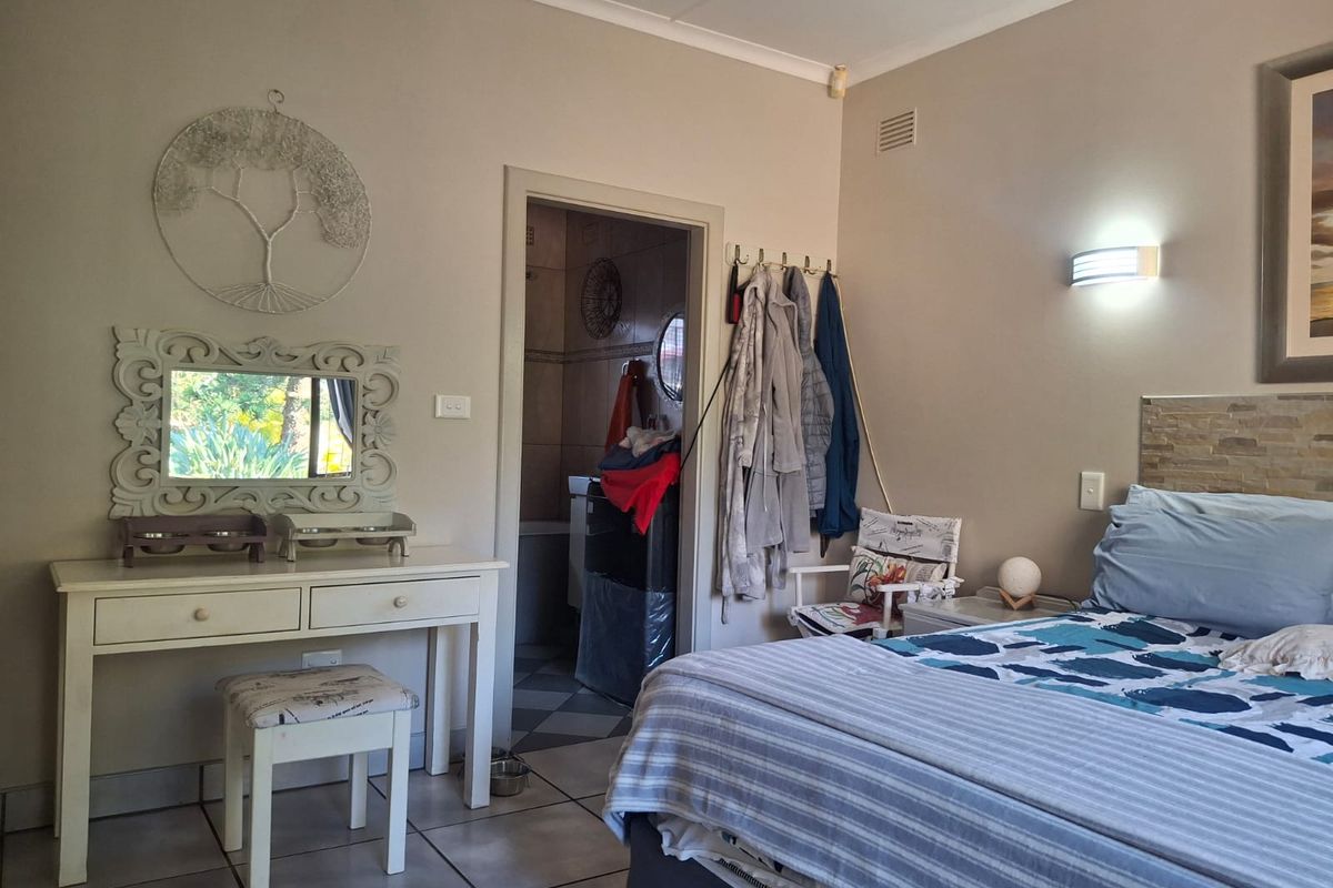 A bedroom featuring tiled flooring, a stone-tiled headboard accent, and direct access to an en-suite bathroom.