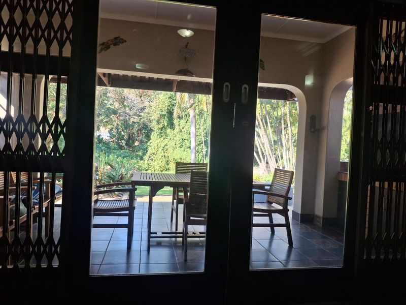 A covered patio area featuring tiled flooring and arched architectural details, providing a seamless transition to the garden space.