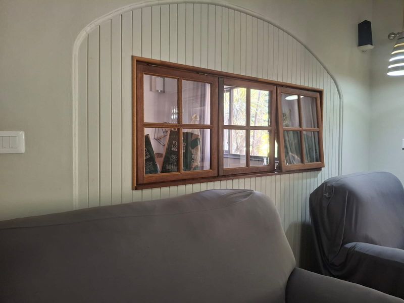 A living room interior featuring a distinctive arched wall recess with beadboard paneling and a timber-framed casement window.