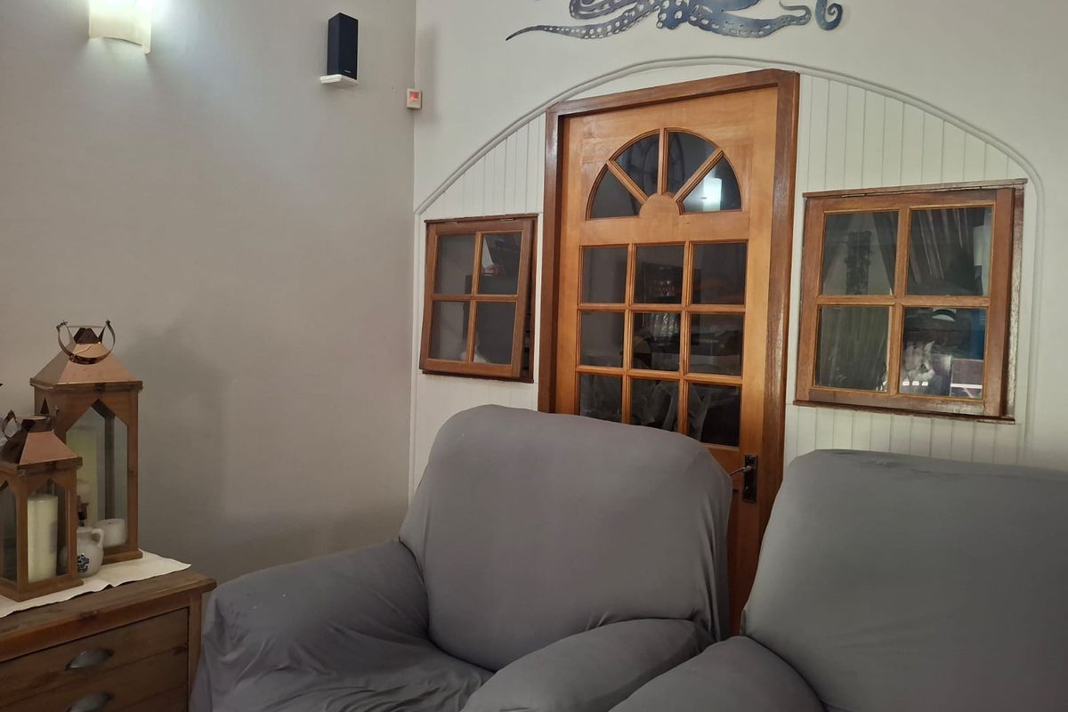 A living room area featuring a distinctive arched timber-framed glass door flanked by matching timber-framed windows and wall-mounted lighting.