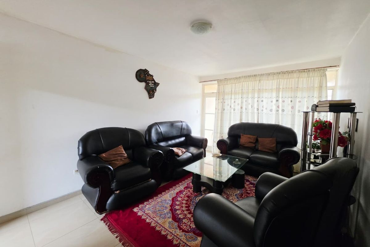 A living room featuring tiled flooring and a sliding glass door with curtains, providing access to the exterior.