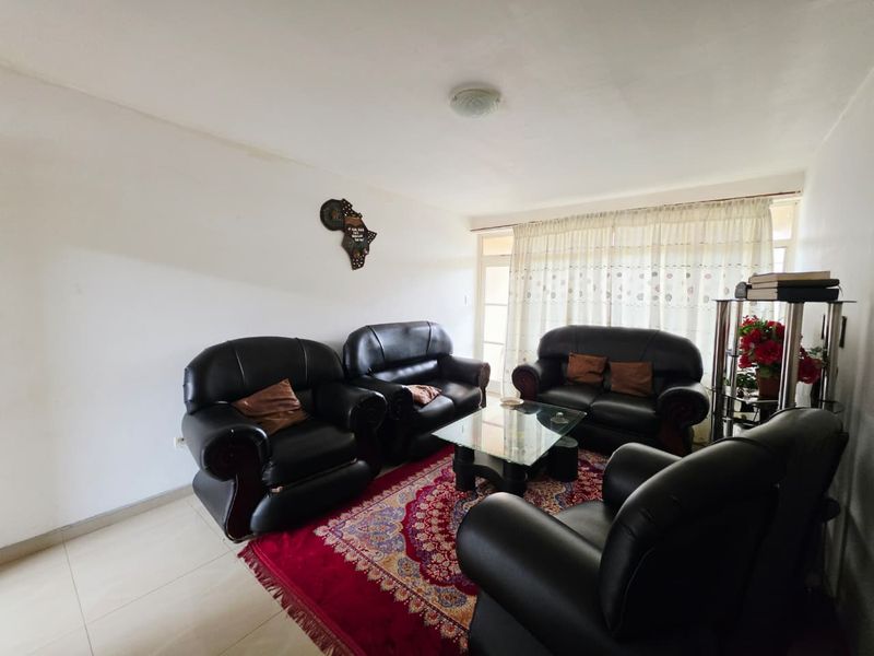 A living room featuring tiled flooring and a sliding glass door with curtains, providing access to the exterior.