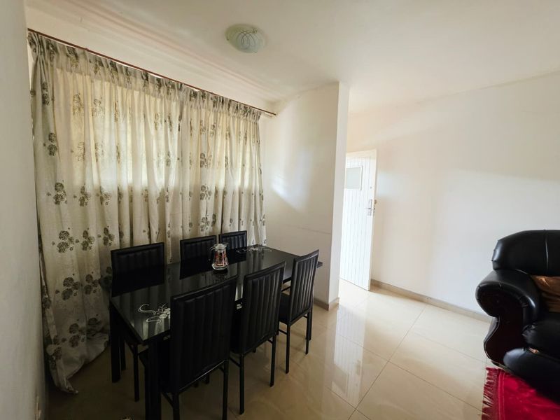A functional dining area featuring tiled flooring and natural light, providing a neutral space ready for personalization.