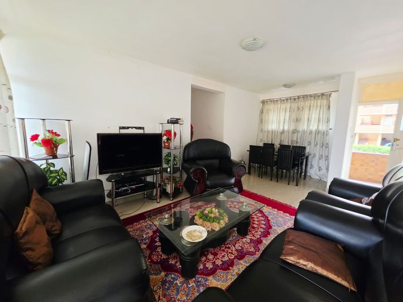 An open-plan living and dining area featuring neutral walls and tiled flooring, providing a functional space for relaxation and meals.