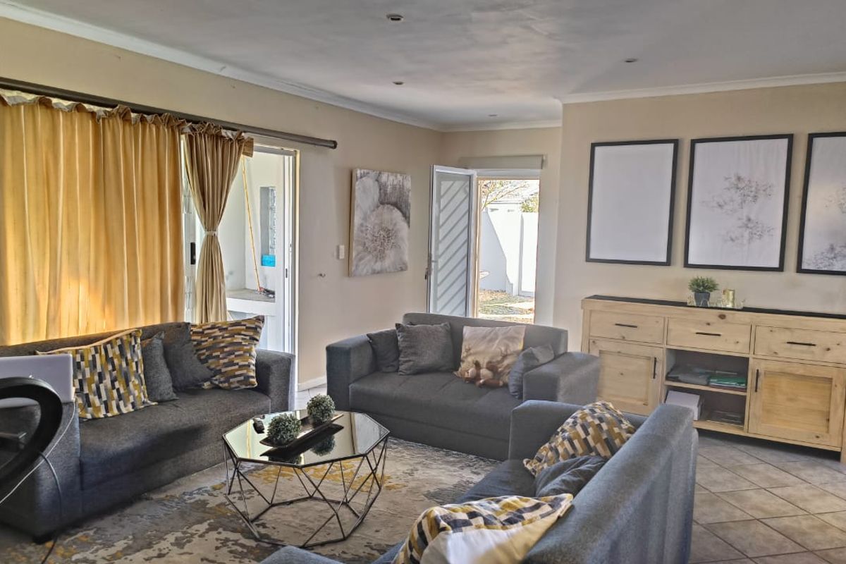 A spacious living room featuring tiled flooring, recessed lighting, and direct access to the outdoor area through a sliding glass door.