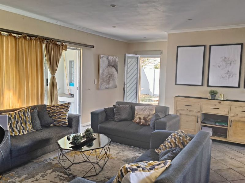 A spacious living room featuring tiled flooring, recessed lighting, and direct access to the outdoor area through a sliding glass door.