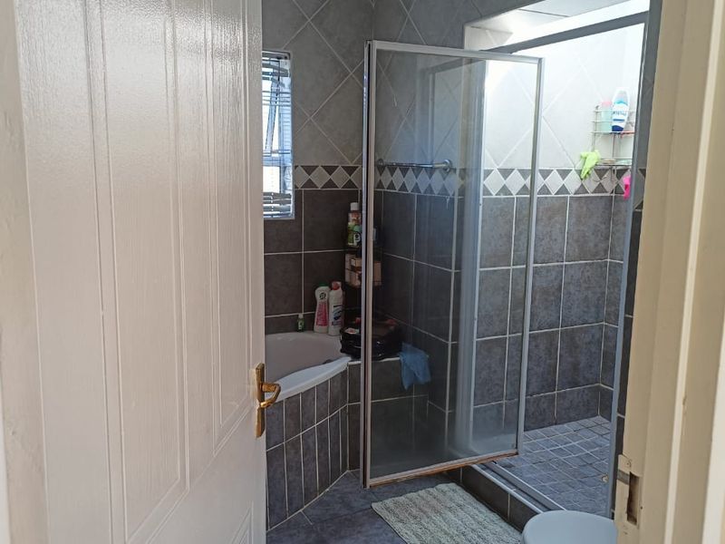 A functional bathroom featuring a corner bathtub, a separate walk-in shower with a glass enclosure, and neutral tiled finishes throughout.