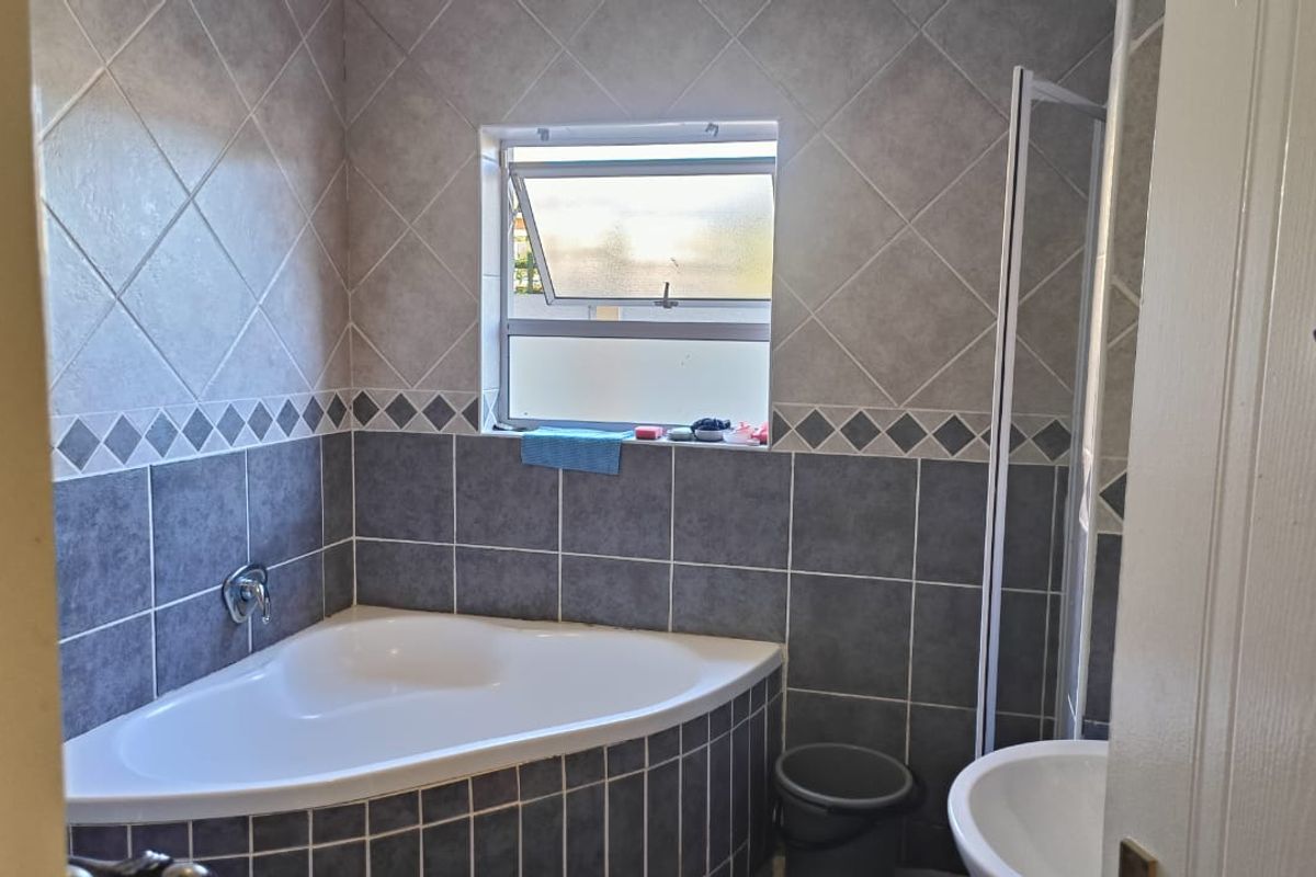 A functional bathroom featuring a corner bathtub, tiled wall finishes, a shower enclosure, and a pedestal basin.