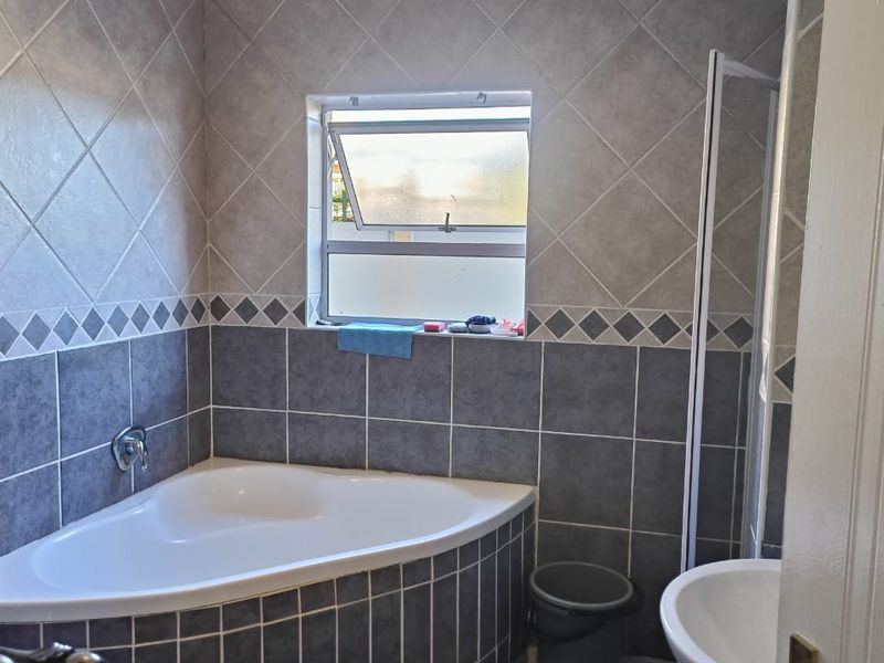 A functional bathroom featuring a corner bathtub, tiled wall finishes, a shower enclosure, and a pedestal basin.