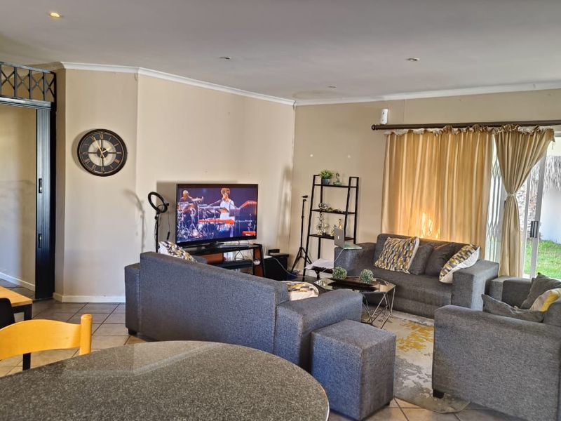 Open plan living area featuring tiled flooring, recessed lighting, and direct access to the garden through a sliding glass door.