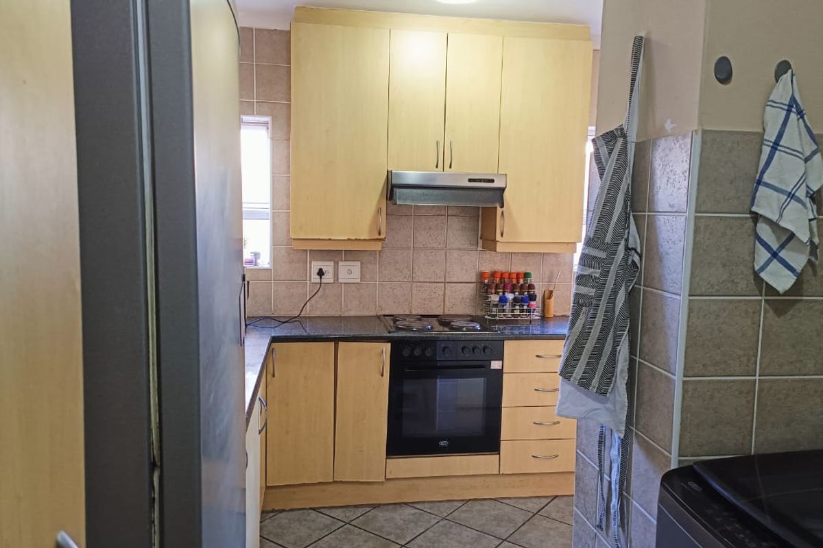 A functional kitchen featuring light wood cabinetry, granite countertops, a built-in oven with hob, and a tiled backsplash.