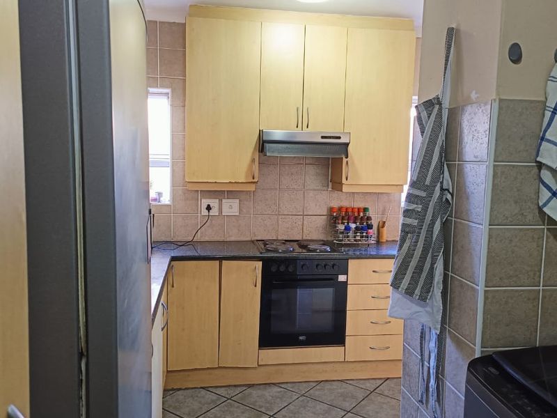 A functional kitchen featuring light wood cabinetry, granite countertops, a built-in oven with hob, and a tiled backsplash.