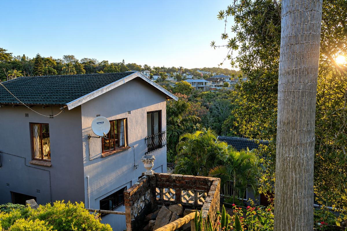 Rear view of a two-story house featuring a tiled roof, satellite dish, and a brick masonry balcony structure overlooking a lush green landscape.