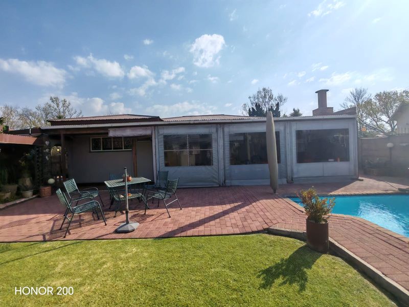 Outdoor patio area featuring paved flooring, retractable weather enclosures, and direct access to a swimming pool.