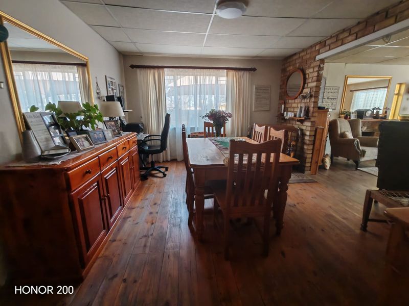 Dining room featuring exposed brick wall detailing, timber flooring, and a drop ceiling, offering a rustic aesthetic with potential for modern updates.
