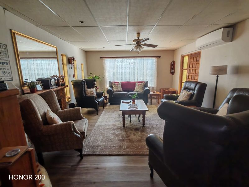 A spacious living room featuring a fireplace mantel, split-system air conditioning, and a drop ceiling, offering a comfortable and functional layout.