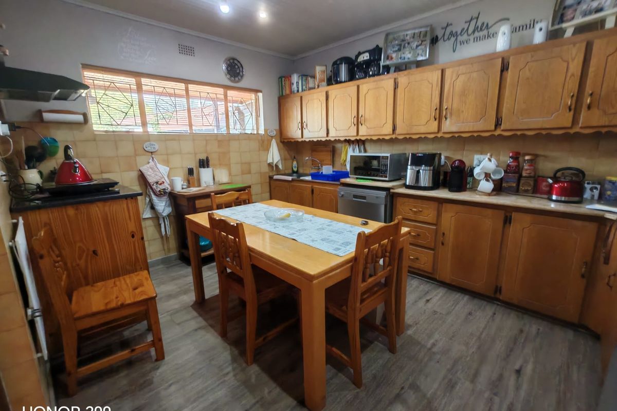 A functional kitchen featuring traditional wooden cabinetry, laminate countertops, tiled backsplash, and integrated dishwasher, offering a classic layout with space for a dining table.