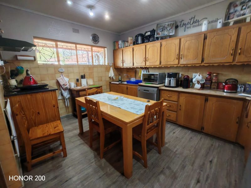 A functional kitchen featuring traditional wooden cabinetry, laminate countertops, tiled backsplash, and integrated dishwasher, offering a classic layout with space for a dining table.