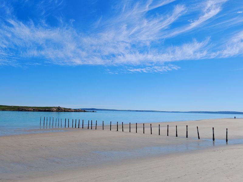 A scenic view of a pristine sandy beach and calm blue water, showcasing the natural coastal landscape of the vacant land property.