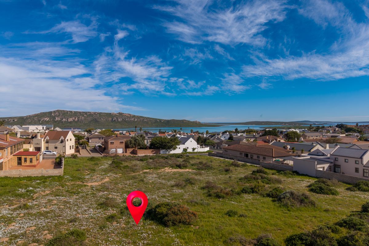 An aerial view of a vacant residential plot situated in a coastal neighborhood with scenic landscape views.