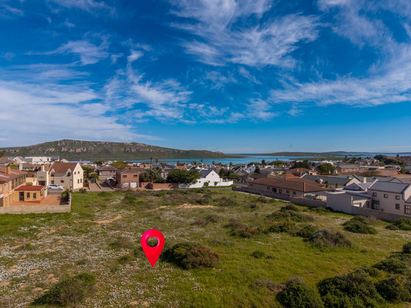 An aerial view of a vacant residential plot situated in a coastal neighborhood with scenic landscape views.