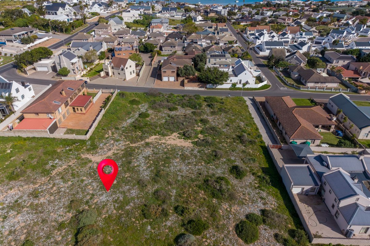 An aerial view of a vacant residential plot situated in a developed coastal neighborhood, offering potential for new construction.