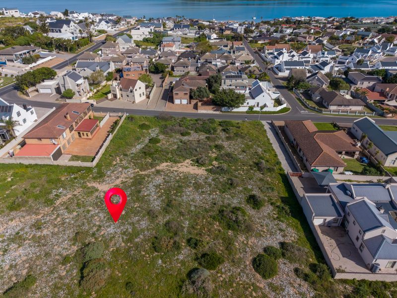 An aerial view of a vacant residential plot situated in a developed coastal neighborhood, offering potential for new construction.