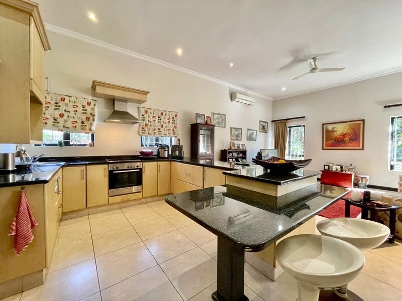 Spacious open-plan kitchen and living area featuring granite countertops, built-in oven, extractor fan, and neutral tiled flooring throughout.