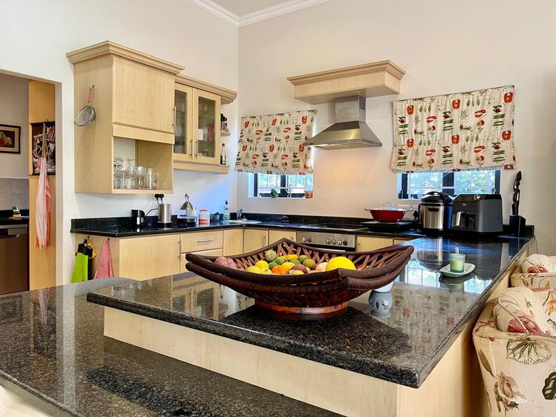 A functional kitchen featuring light wood cabinetry, dark granite countertops, and integrated stainless steel appliances, offering a practical layout for daily cooking.