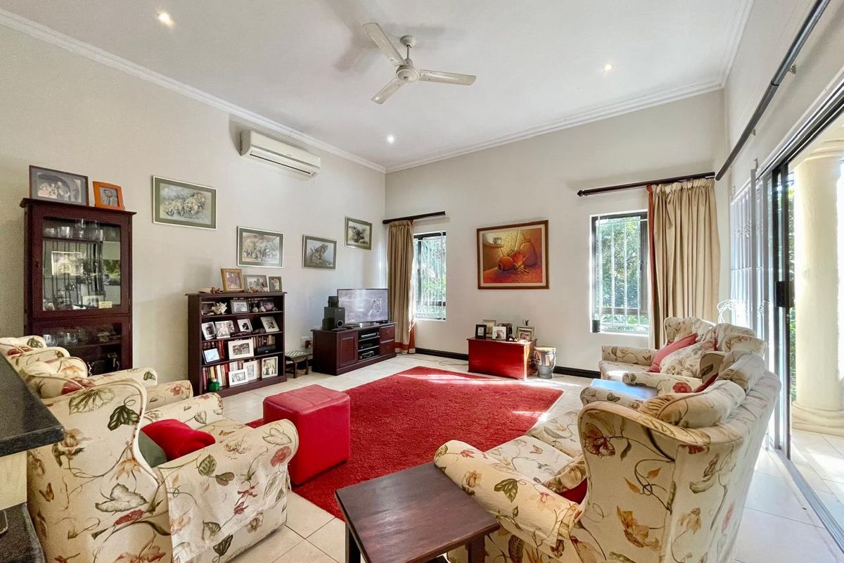 A spacious living room featuring tiled flooring, a ceiling fan, split system air conditioning, and large sliding glass doors providing natural light.