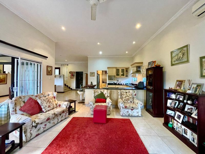 Spacious open-plan living area featuring tiled floors, recessed lighting, and a functional kitchen with built-in cabinetry, seamlessly connecting to the living space.