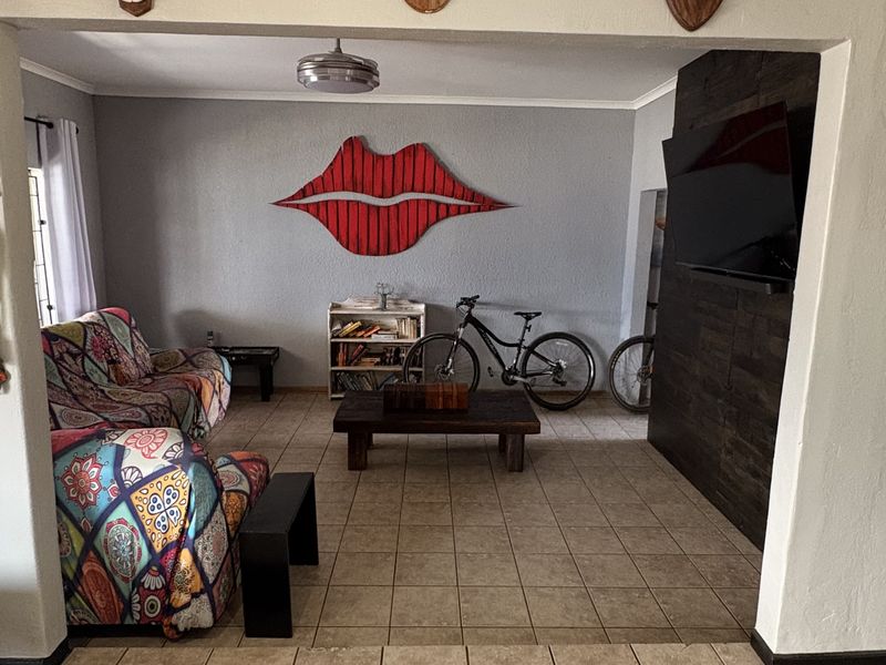 A living room featuring tiled flooring and a dark feature wall, providing a neutral base for potential interior updates.