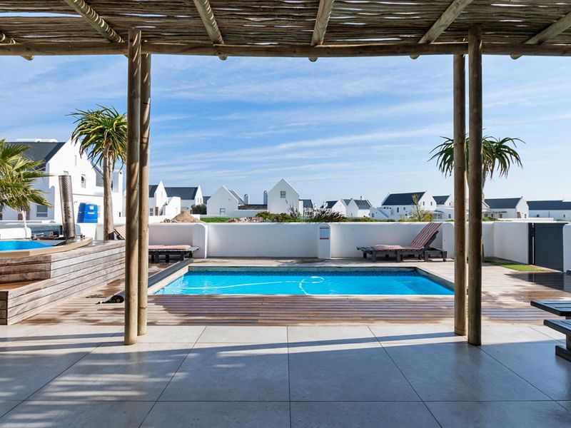 Outdoor entertainment area featuring a swimming pool, timber decking, and a covered patio with a rustic timber pergola.