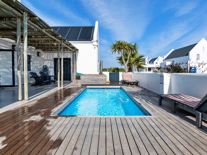 Outdoor pool area featuring timber decking, a covered pergola, and solar panels on the roof, providing a functional space for relaxation and entertainment.