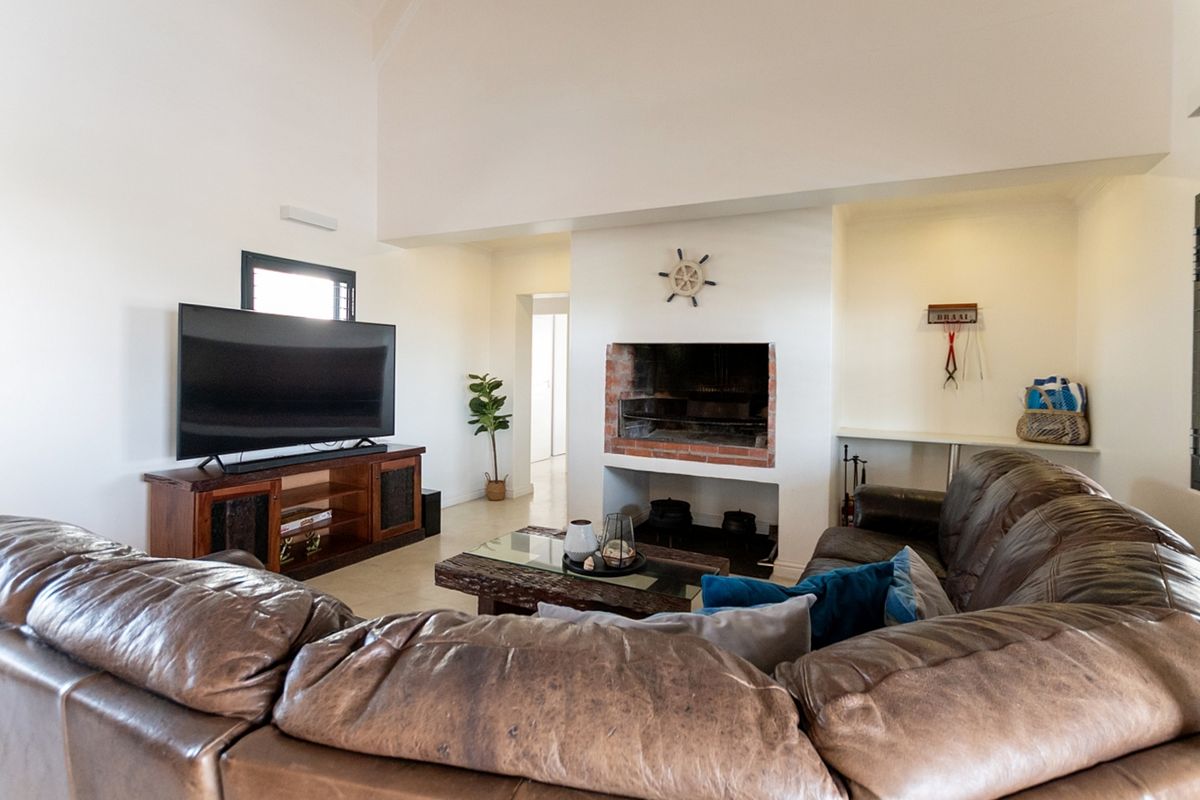 Spacious living room featuring a vaulted ceiling and a traditional built-in brick fireplace, creating a cozy and inviting atmosphere.