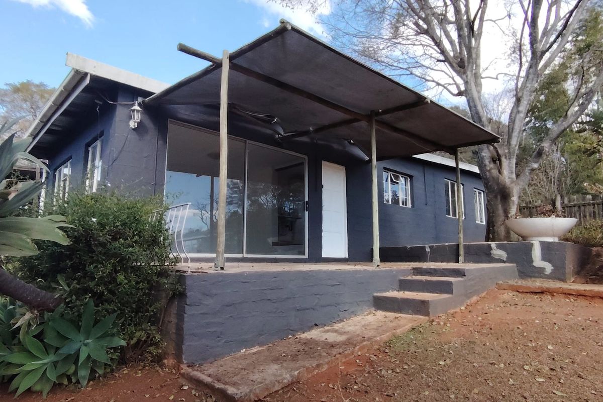 Rear view of the cottage featuring a covered patio area with sliding glass doors and concrete steps leading to the garden.
