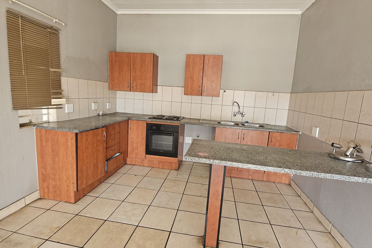 A functional kitchen featuring laminate cabinetry, granite countertops, a built-in oven, and a breakfast bar, requiring minor cosmetic updates to refresh the space.