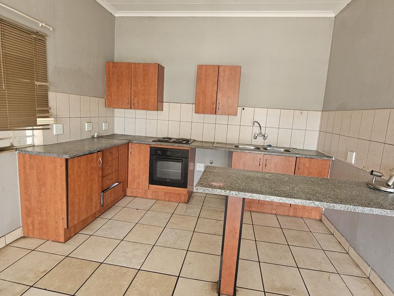 A functional kitchen featuring laminate cabinetry, granite countertops, a built-in oven, and a breakfast bar, requiring minor cosmetic updates to refresh the space.