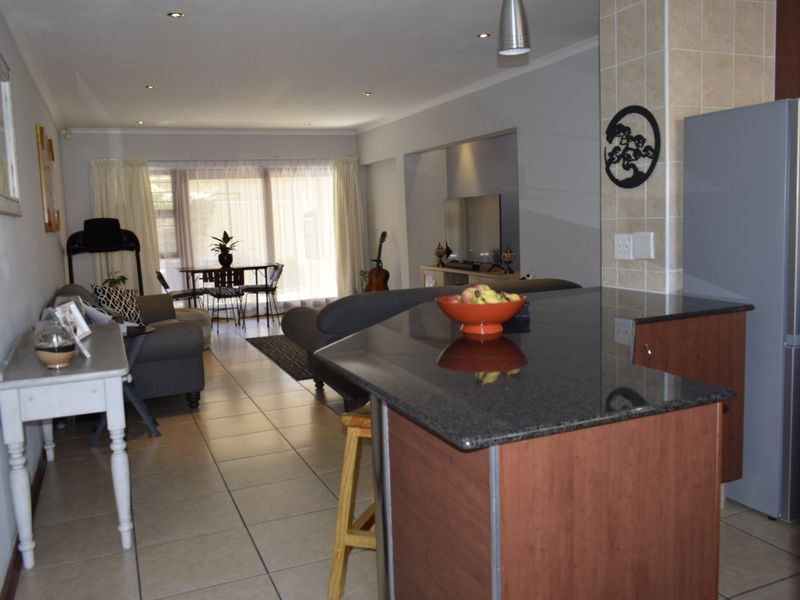 Open-plan living area featuring a kitchen island with granite countertops, tiled flooring throughout, and recessed lighting, creating a functional and connected living space.