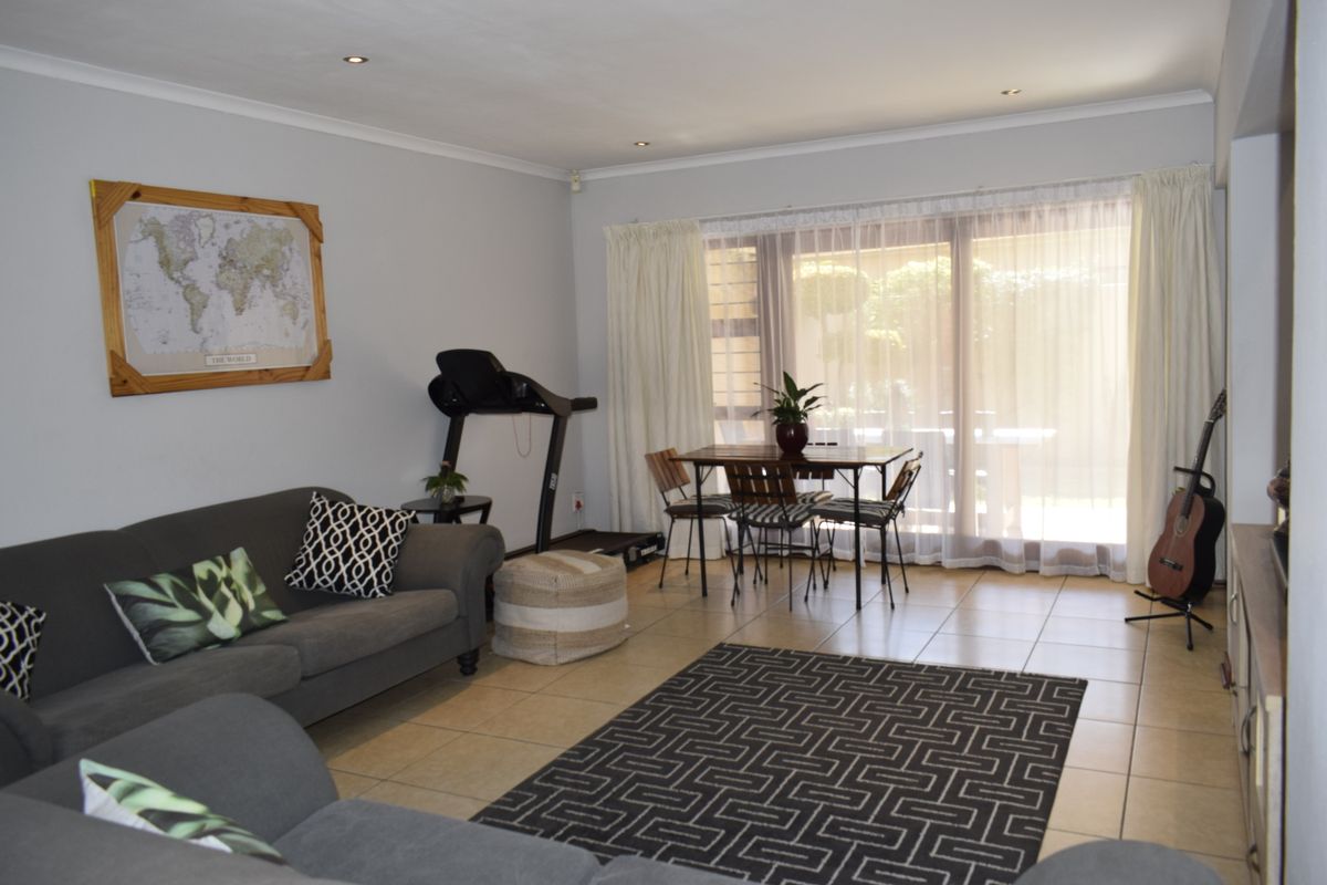 A spacious living area featuring tiled flooring, recessed downlighting, and a large sliding glass door providing access to the outdoor space.
