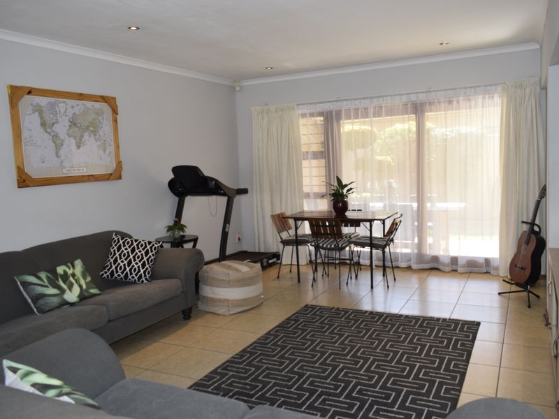 A spacious living area featuring tiled flooring, recessed downlighting, and a large sliding glass door providing access to the outdoor space.