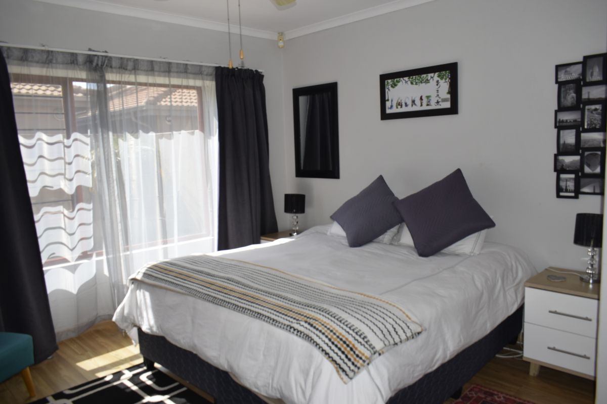 A well-lit bedroom featuring laminate flooring, a ceiling fan, and a sliding glass door providing access to the exterior.