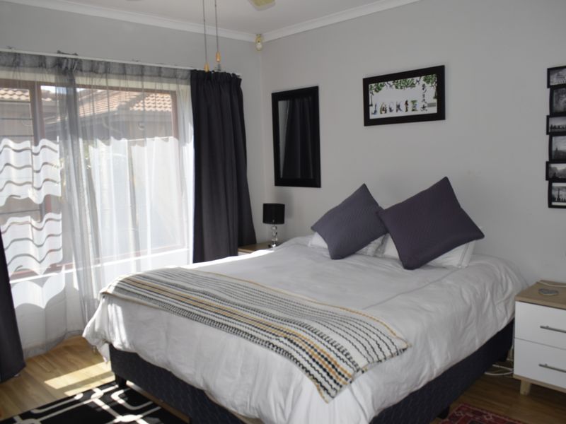A well-lit bedroom featuring laminate flooring, a ceiling fan, and a sliding glass door providing access to the exterior.