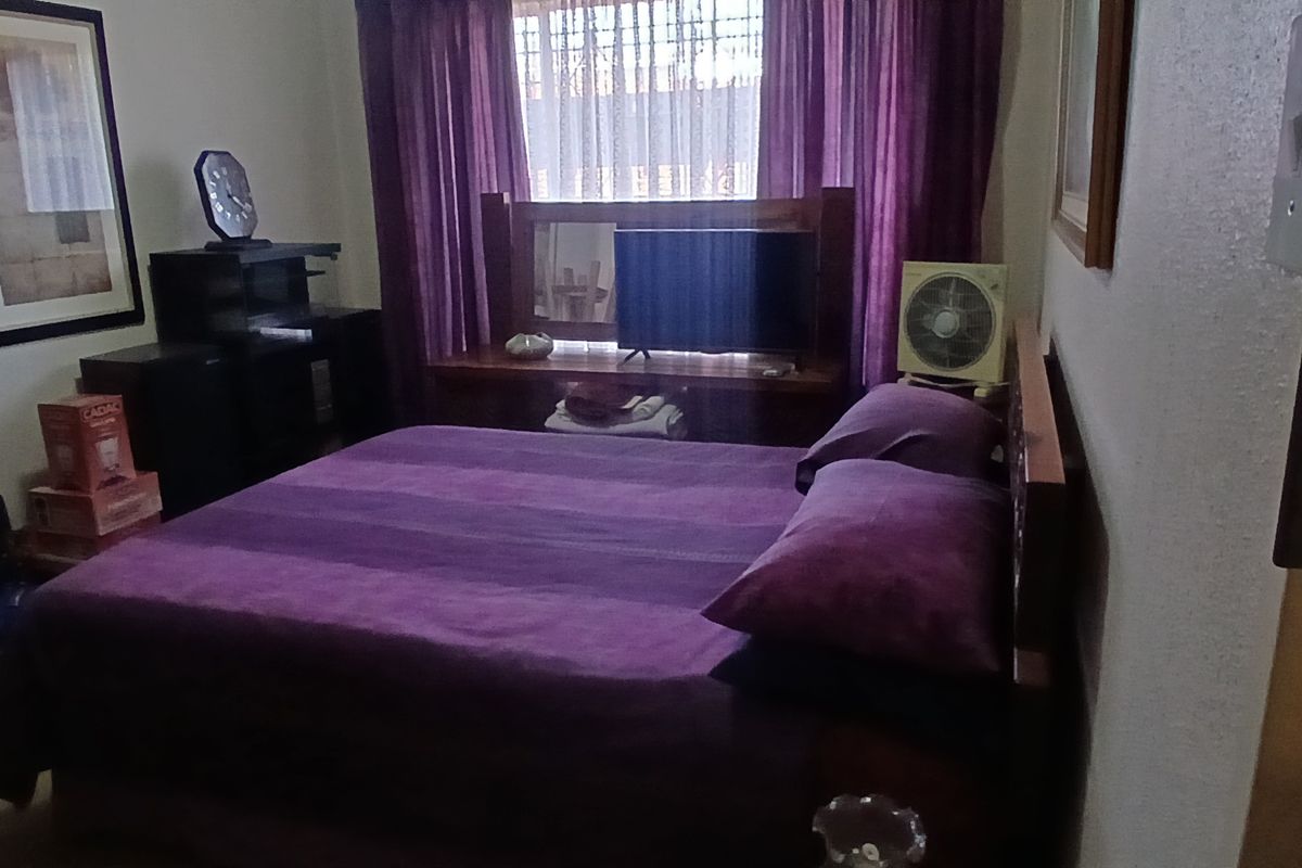 A standard bedroom featuring a window with curtain rails, providing natural light and a functional layout for a sleeping area.