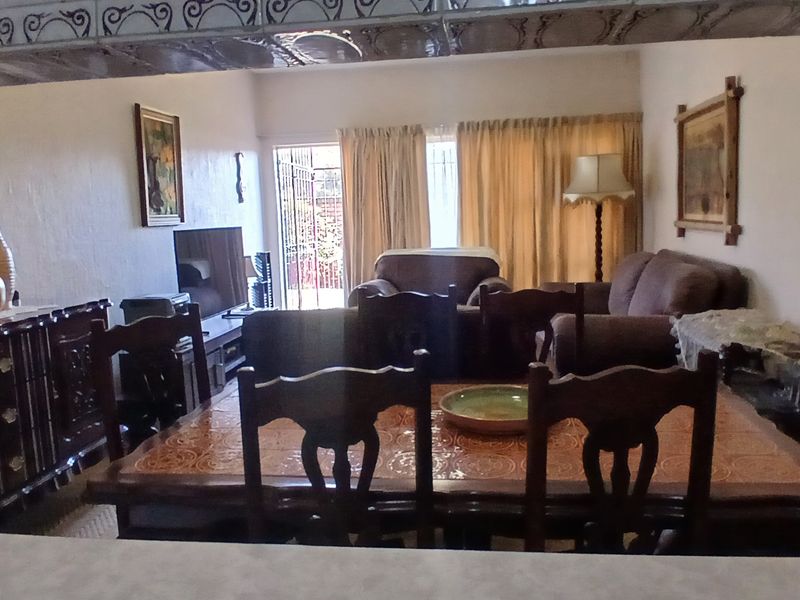 Open plan living and dining area featuring tiled floors, decorative ceiling details, and access to an outdoor area through a security gate.