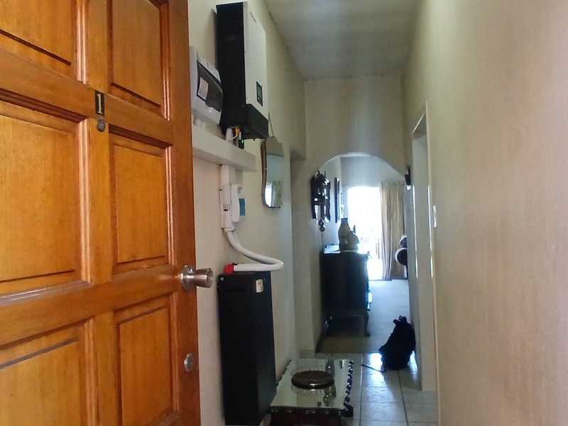 Entrance hallway featuring a timber panelled front door, tiled flooring, and wall-mounted inverter and distribution board infrastructure.