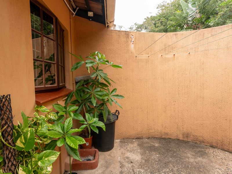 A functional outdoor utility area featuring a curved masonry wall, concrete flooring, and an integrated washing line, suitable for laundry or storage purposes.