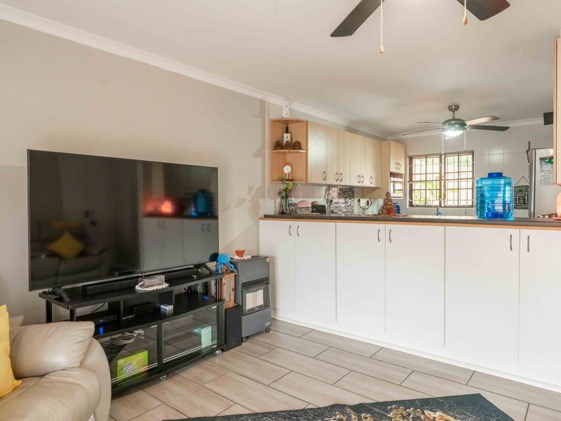 Open plan living area featuring tiled flooring, ceiling fans, and a functional kitchen with built-in cabinetry and a breakfast bar.